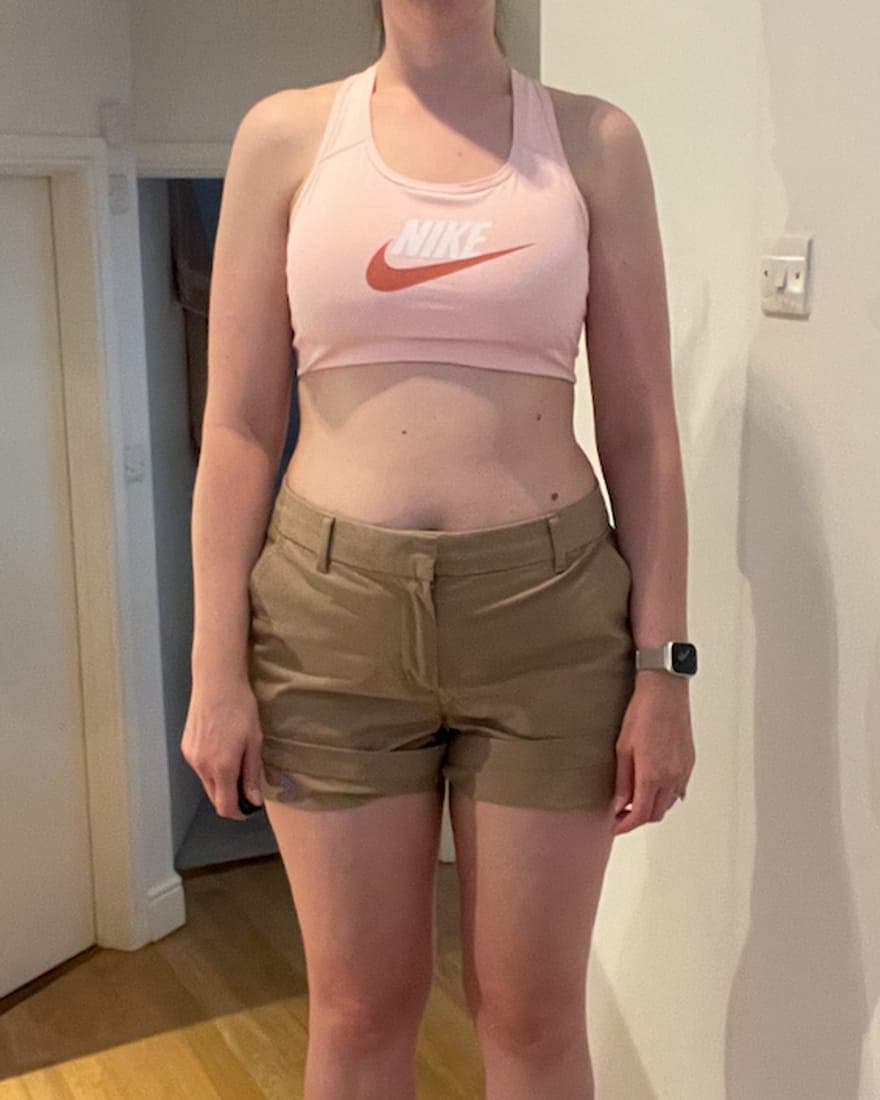 Torso-and-legs photo of Anna in a hallway in a sports bra and shorts at her heaviest recorded weight